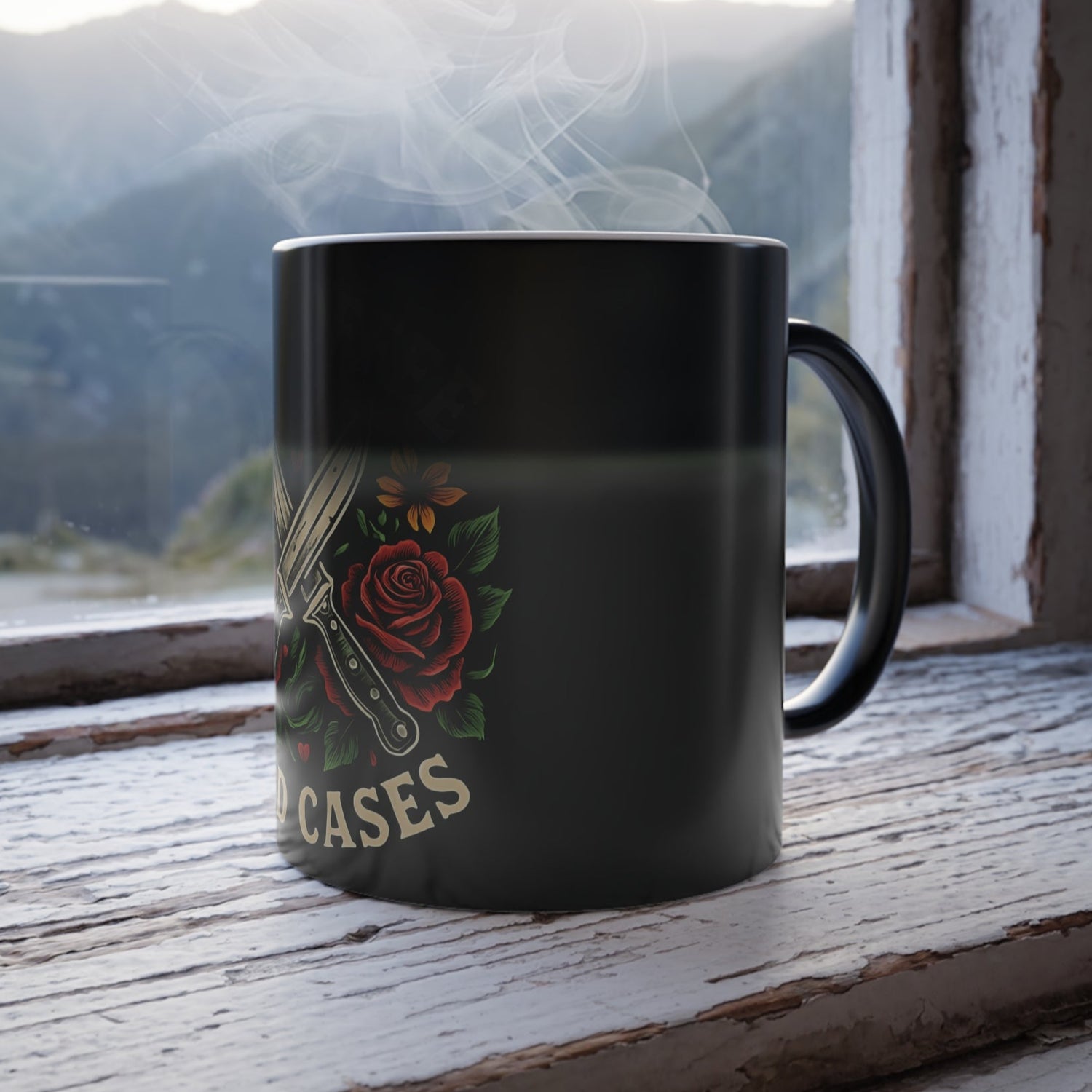 Black mug with a rose design and 'CASES' text on a windowsill with a mountain view.